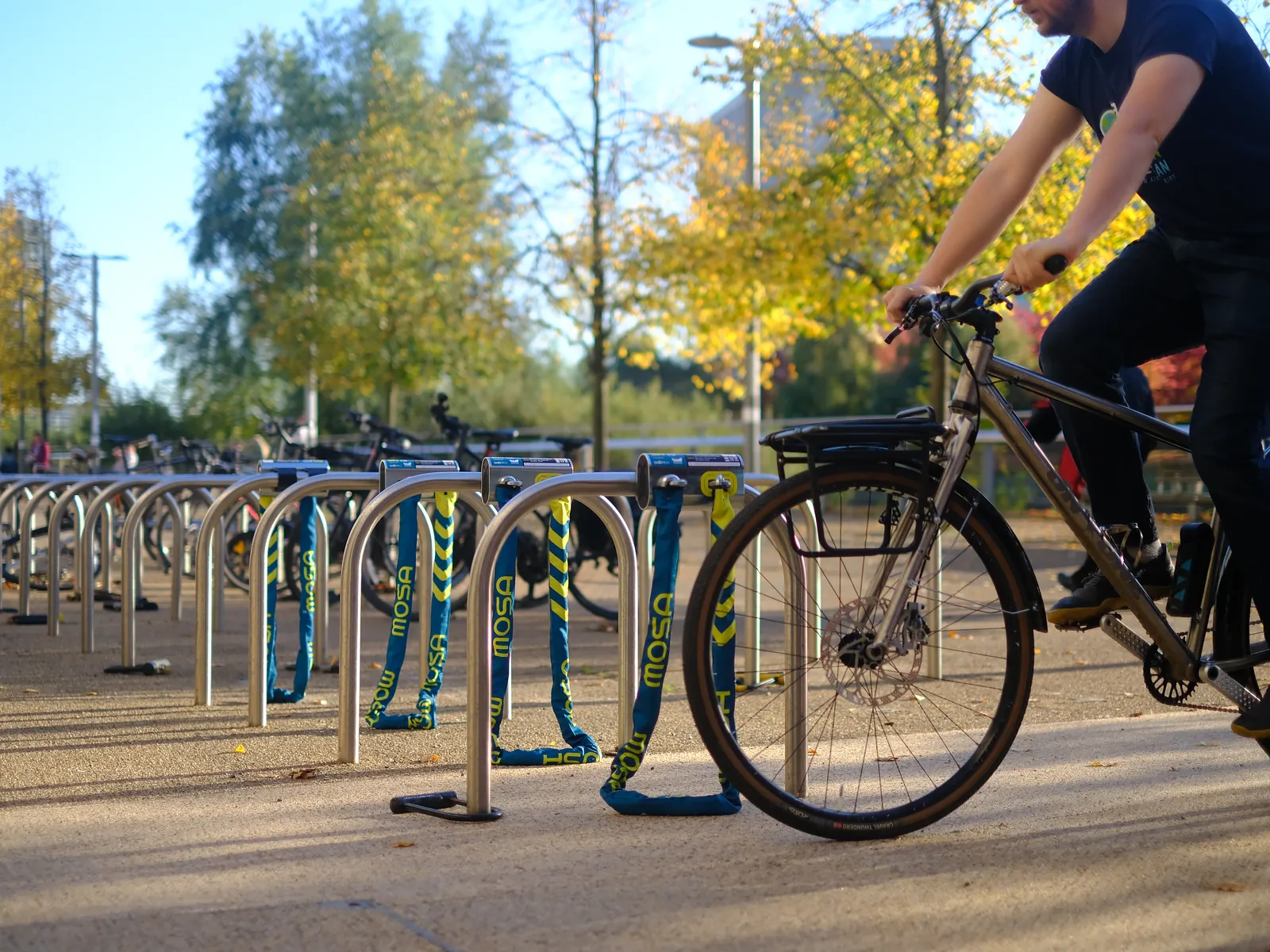 A cyclist riding past a long row of Mosa docks on the racks at Queen Elizabeth Olympic Park.