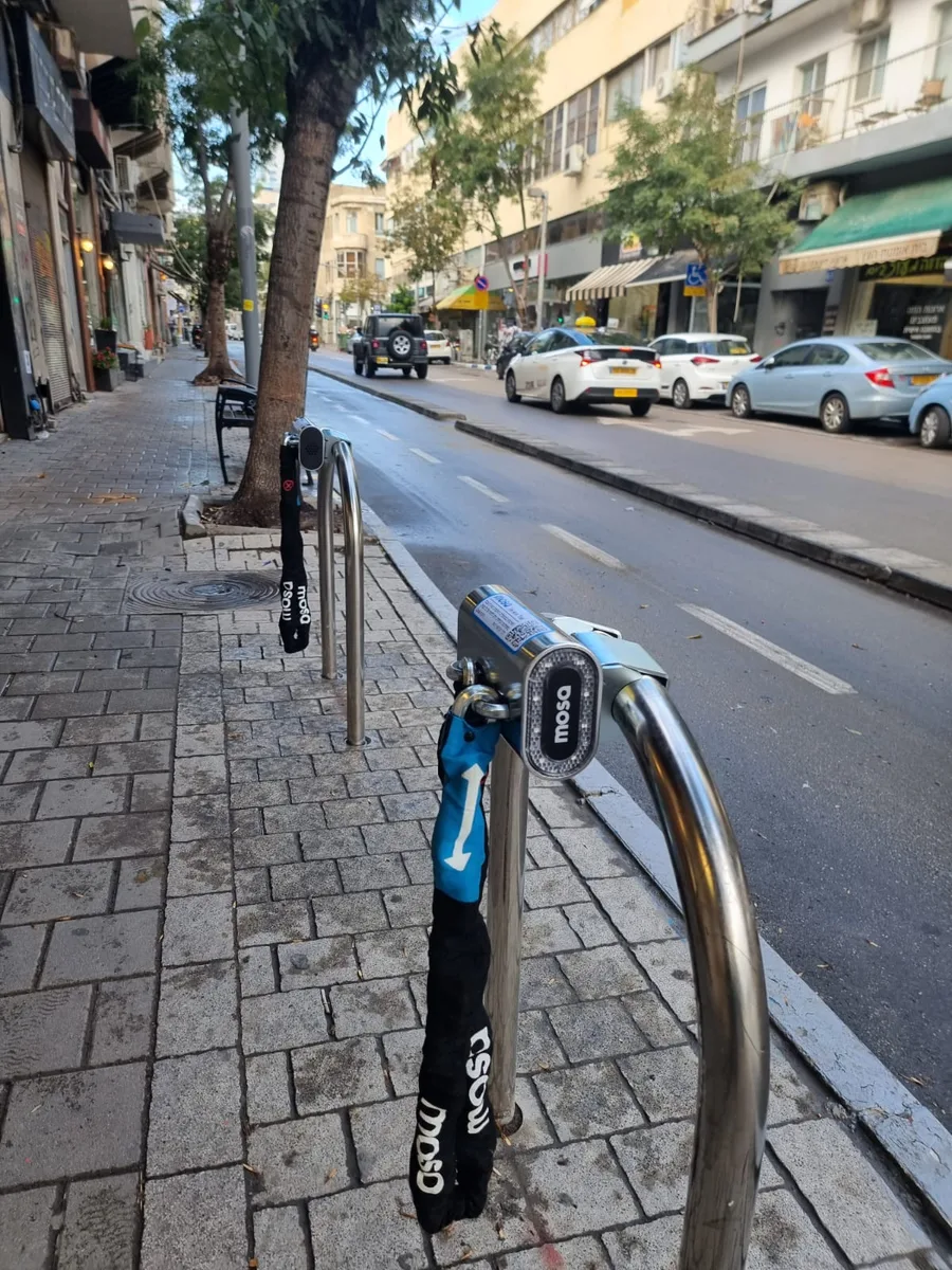 Mosa docks with their chains on two public racks beside a Tel Aviv cycle lane.