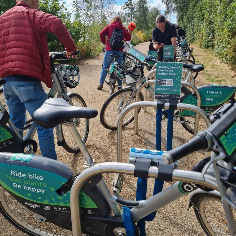 Riders unlocking shared bikes from Mosa docks on the path at RHS Bridgewater.
