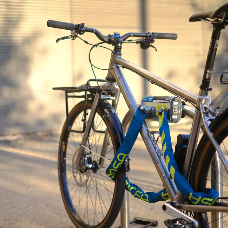 A bike locked to a rack with the blue and yellow chain of a Mosa dock.